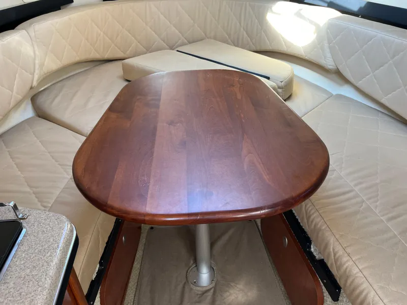 Slide: The Image of 2007 Sea Ray 270 Amberjack cabin with wooden table and beige seating. - 31