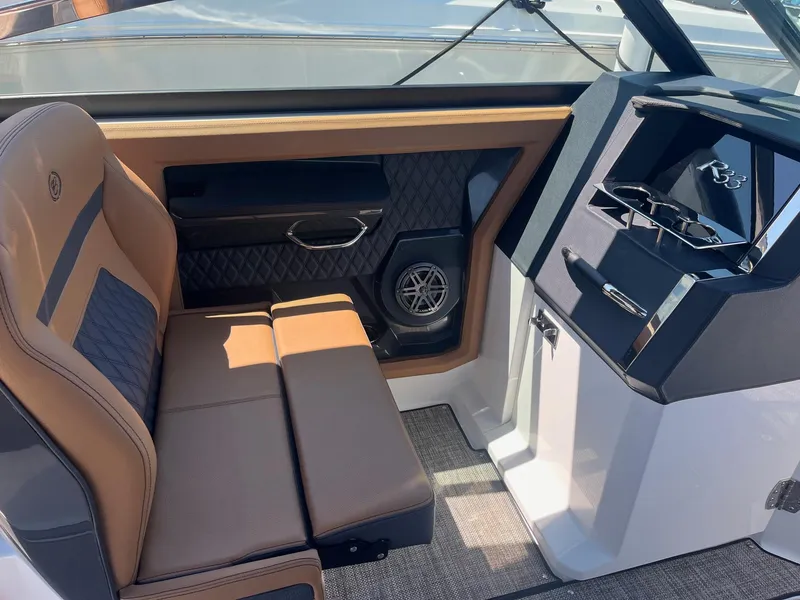 Slide: The Image of 2024 Cobalt R33 boat interior with tan and gray seating, modern dashboard, and speaker system. - 9