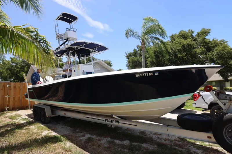 The Image of 2001 Contender 27 Open boat on a trailer, parked outdoors near palm trees. - 1