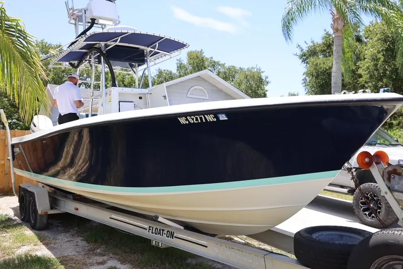 Slide: The Image of 2001 Contender 27 Open boat on trailer, side view, with palm trees in background. - 2