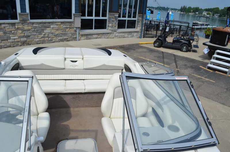 Slide: The Image of 2009 Stingray 205LX boat interior with white seating, docked near a waterfront. - 5