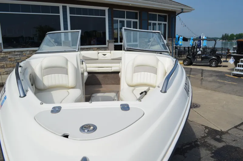 Slide: The Image of 2009 Stingray 205LX boat with white interior, docked near a building. - 7