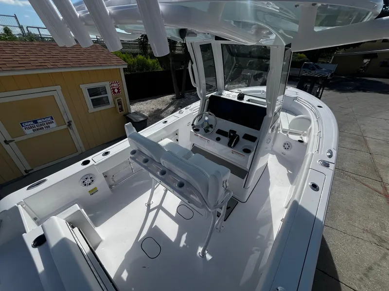 Slide: The Image of 2026 Sportsman Open 212 Center Console boat with sleek design, docked near a yellow shed. - 23