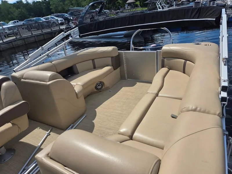 Slide: The Image of 2021 Harris Cruiser 230 pontoon boat with beige seating, docked by the water. - 4