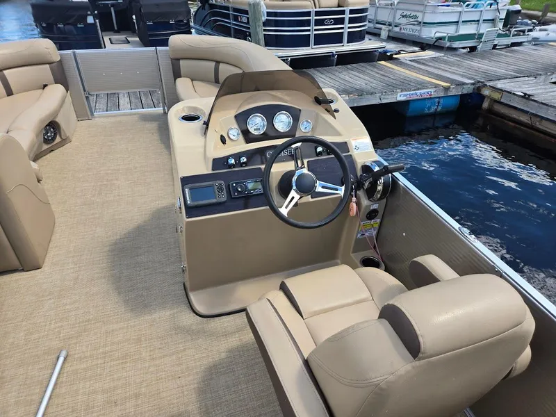 Slide: The Image of 2021 Harris Cruiser 230 boat interior with beige seating and steering console at dock. - 5
