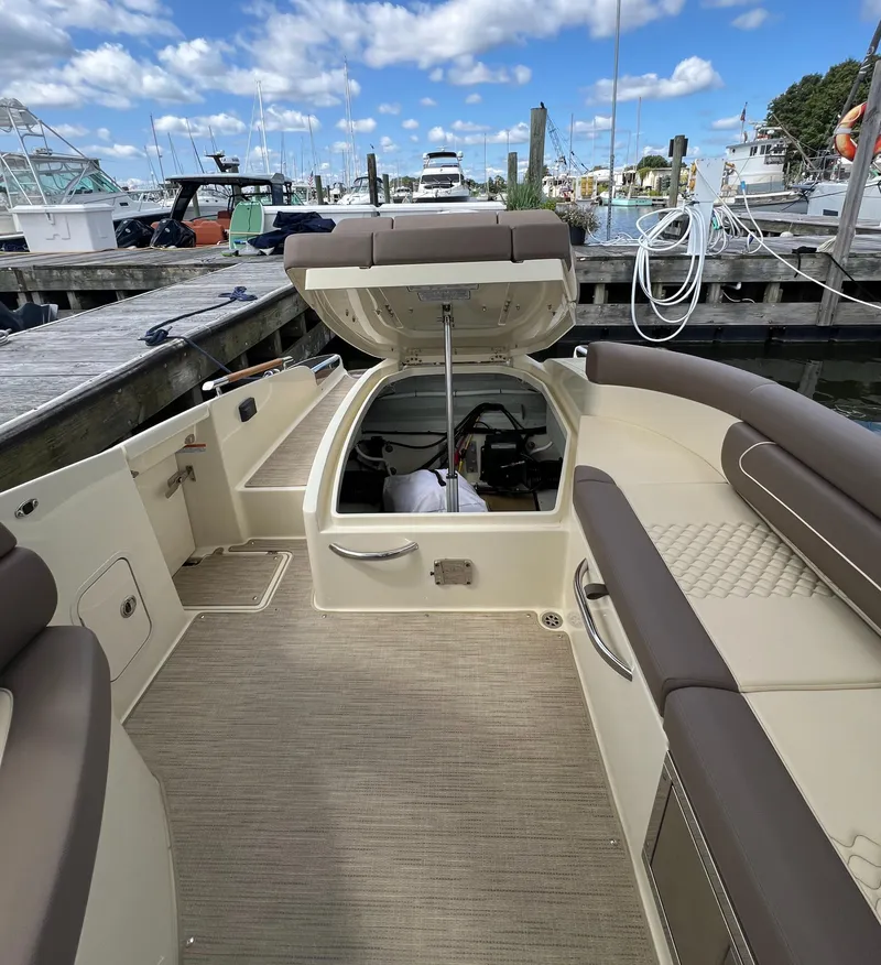 Slide: The Image of 2023 Chris-Craft Launch 28 GT boat interior at marina, open storage compartment, clear sky. - 19