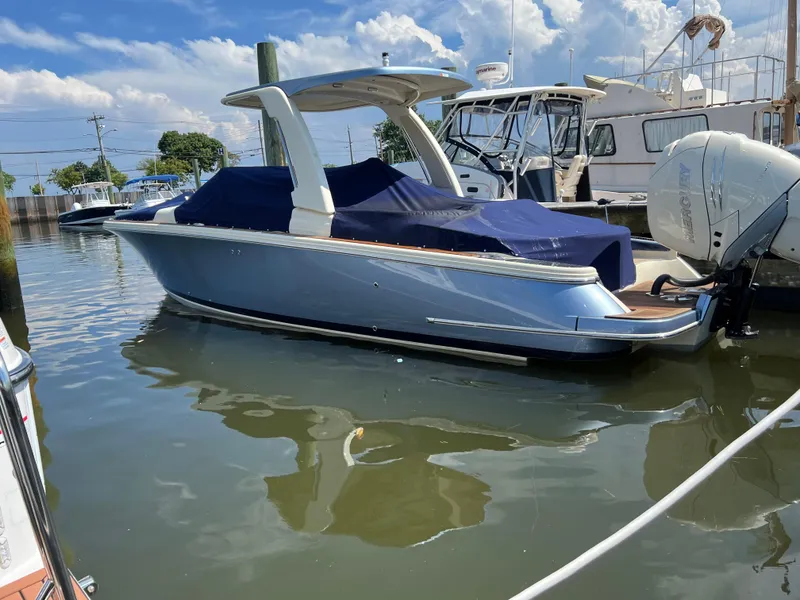 Slide: The Image of 2023 Chris-Craft Launch 28 GT boat docked in marina, covered with blue tarp. - 3
