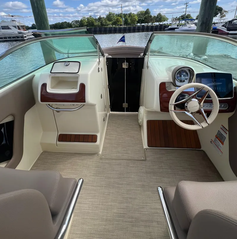 Slide: The Image of 2023 Chris-Craft Launch 28 GT interior with steering wheel and dashboard, docked by the water. - 33