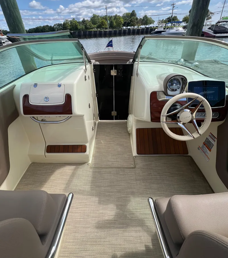 Slide: The Image of 2023 Chris-Craft Launch 28 GT interior with steering wheel and dashboard, docked by the water. - 34