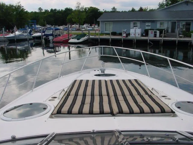 Slide: The Image of 2007 Regal 4460 Commodore yacht docked, featuring striped deck cushions and marina view. - 12