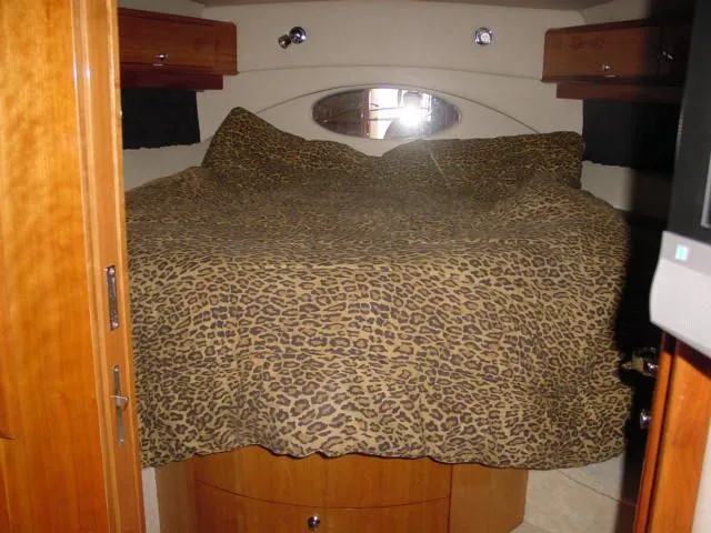 Slide: The Image of 2007 Regal 4460 Commodore cabin with leopard print bedding and wooden cabinetry. - 18