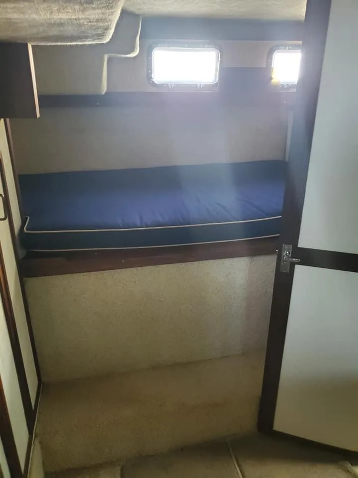 Slide: The Image of 1983 Carver 3207 AFT Cabin Motor Yacht interior with a blue-cushioned bunk bed. - 17