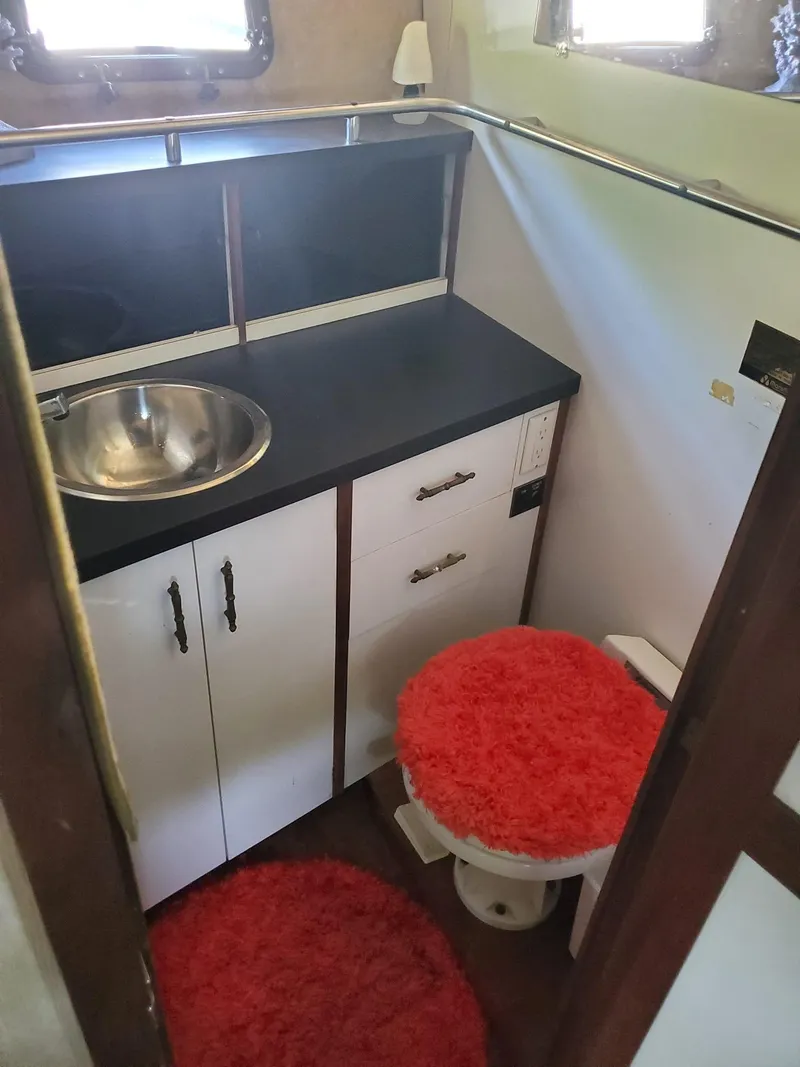 Slide: The Image of 1983 Carver 3207 AFT Cabin Yacht bathroom with sink, cabinets, and red rugs. - 11