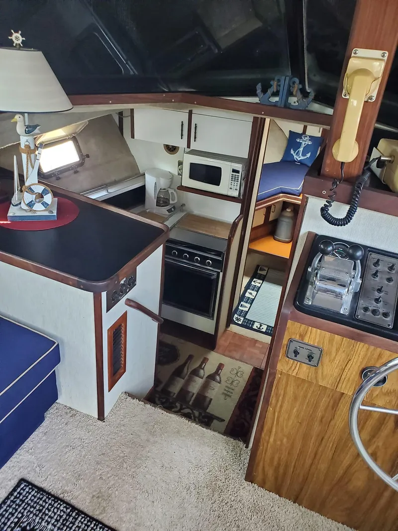Slide: The Image of 1983 Carver 3207 AFT Cabin Motor Yacht interior with kitchen, seating, and nautical decor. - 15