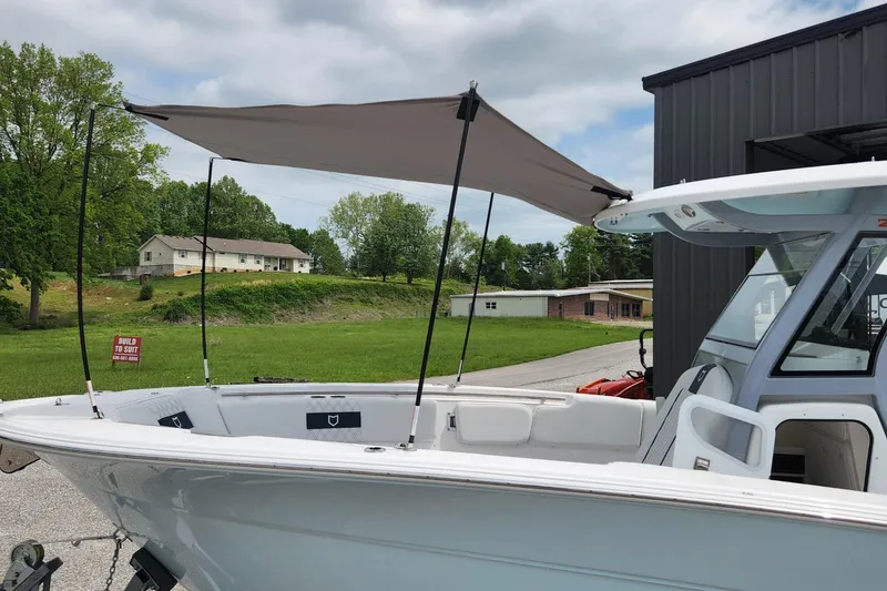 Slide: The Image of 2025 Sea Fox 288 Commander boat with canopy, docked near a building. - 24