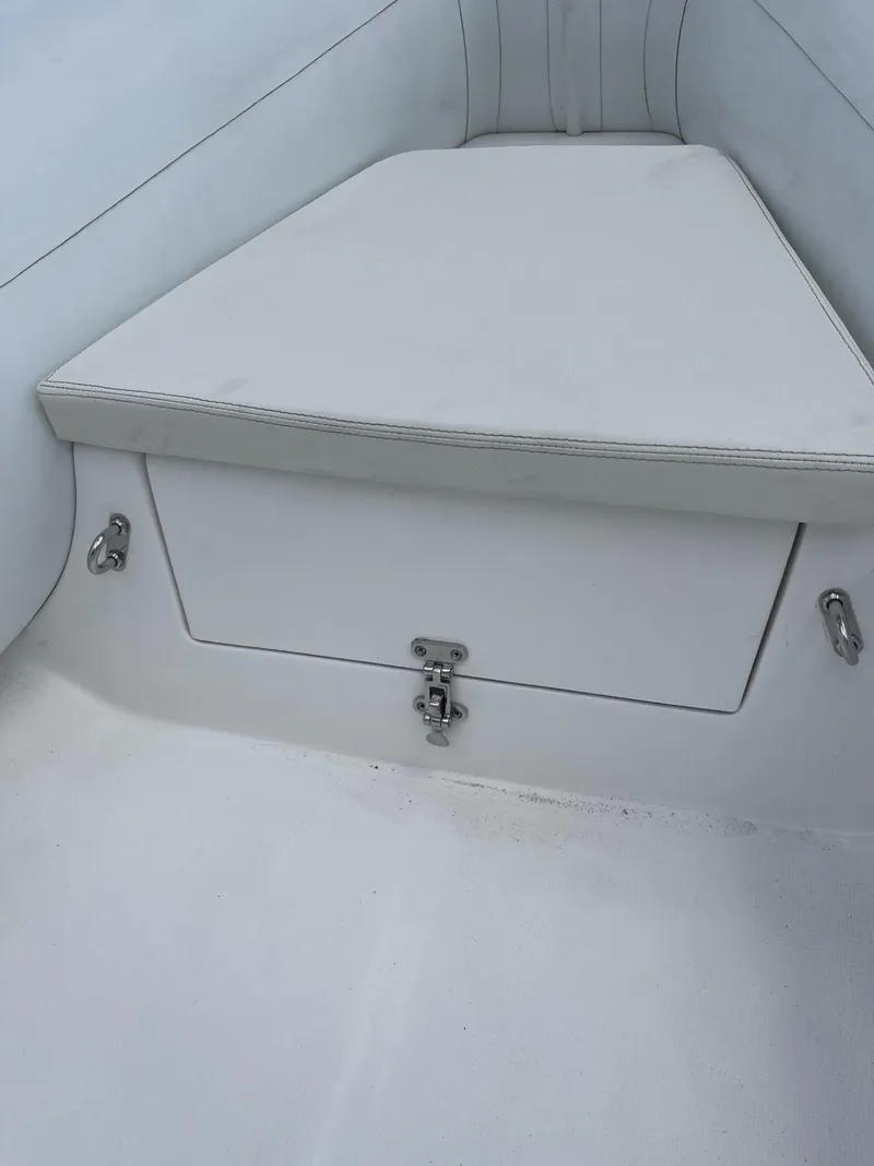 Slide: The Image of Apex A12 2021 boat interior with white cushioned seating and storage compartment. - 13