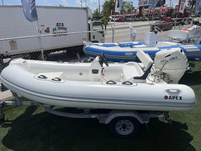 Slide: The Image of 2021 Apex A12 inflatable boat with Suzuki outboard motor on display. - 2