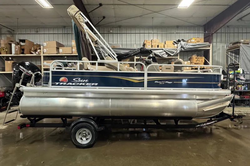 The Image of 2023 Sun Tracker Bass Buggy 18 DLX pontoon boat in a warehouse setting. - 0