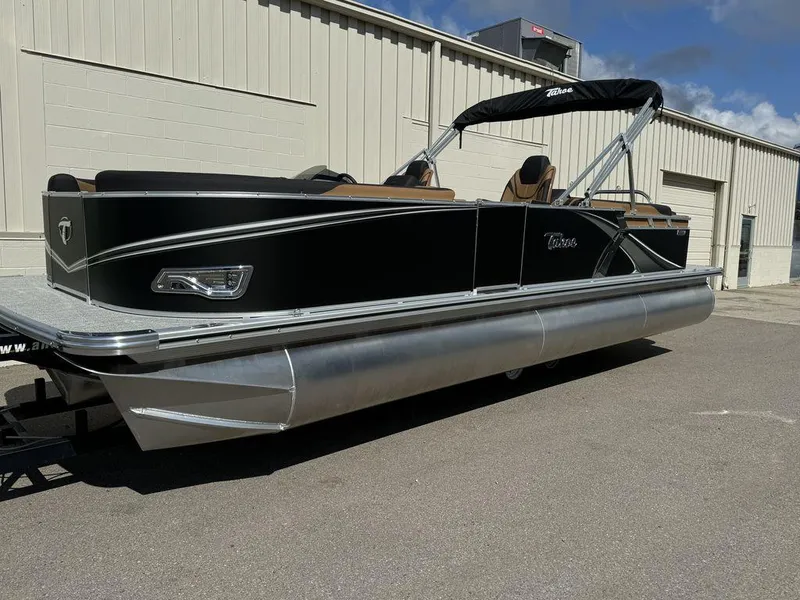 Slide: The Image of 2025 Tahoe LTZ 2585 QL pontoon boat with black exterior, parked outdoors. - 1