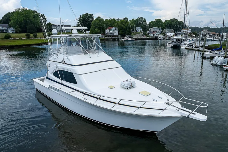 Slide: The Image of 2005 Bertram 450 Convertible yacht docked in a serene marina setting. - 0