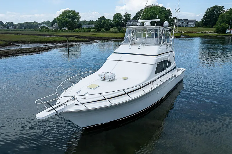 Slide: The Image of 2005 Bertram 450 Convertible yacht on calm water, showcasing sleek design and luxury features. - 10