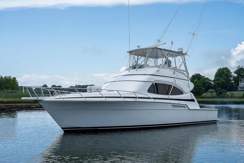 Slide: The Image of 2005 Bertram 450 Convertible yacht on calm water, under a clear sky. - 2