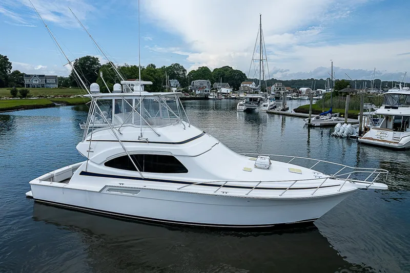 Slide: The Image of 2005 Bertram 450 Convertible yacht docked in a serene marina setting. - 3