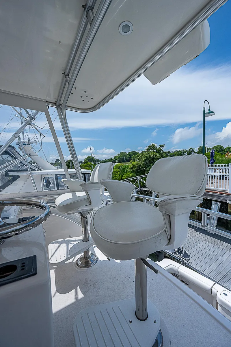 Slide: The Image of 2005 Bertram 450 Convertible yacht with white captain chairs and scenic marina view. - 36