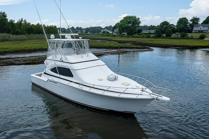 Slide: The Image of 2005 Bertram 450 Convertible yacht on calm water, surrounded by lush greenery. - 4