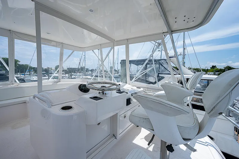 Slide: The Image of 2005 Bertram 450 Convertible yacht helm with white seating and marina view. - 41