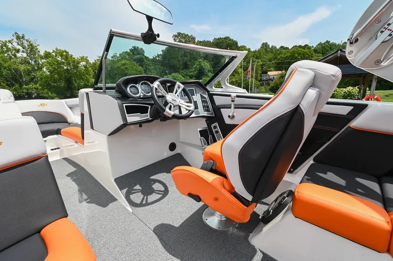 Slide: The Image of 2018 MasterCraft XT23 boat interior with orange and black seating, modern dashboard, and steering wheel. - 31