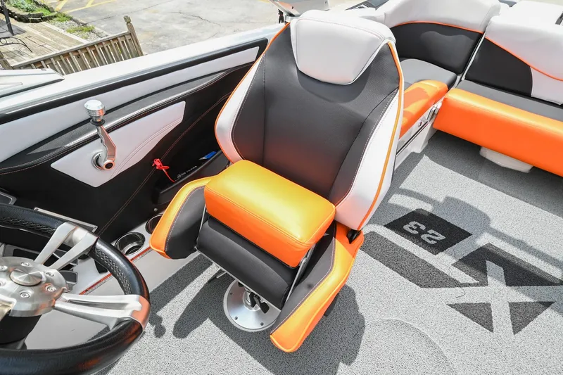 Slide: The Image of 2018 MasterCraft XT23 boat interior with orange and black seating, steering wheel, and modern design. - 35
