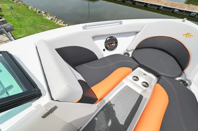 Slide: The Image of 2018 MasterCraft XT23 boat interior with orange and black seating near a lake. - 38