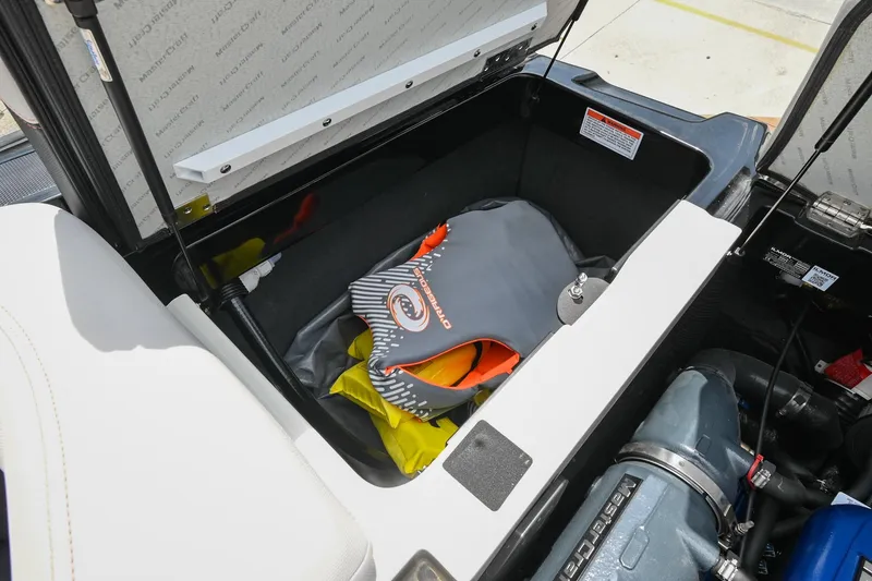 Slide: The Image of 2018 MasterCraft XT23 storage compartment with life jacket and engine view. - 45