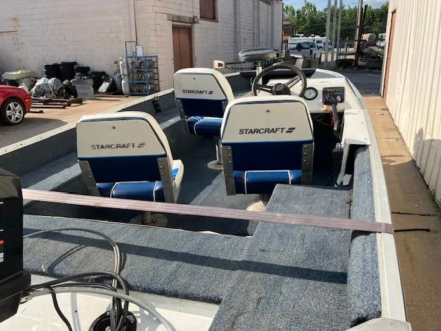 Slide: The Image of 1992 Starcraft FM 160C boat interior with blue and white seating, parked outdoors. - 13