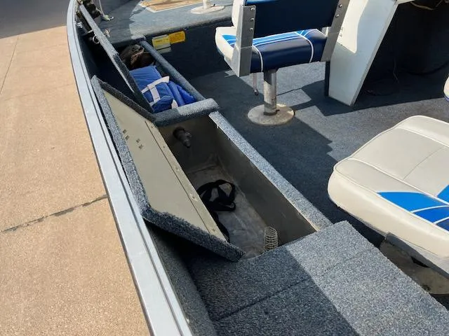 Slide: The Image of 1992 Starcraft FM 160C boat interior with open storage compartments and blue seats. - 9