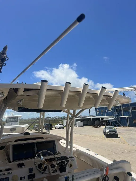 Slide: The Image of 2012 Grady-White 336 Canyon boat dashboard with rod holders under a clear blue sky. - 40