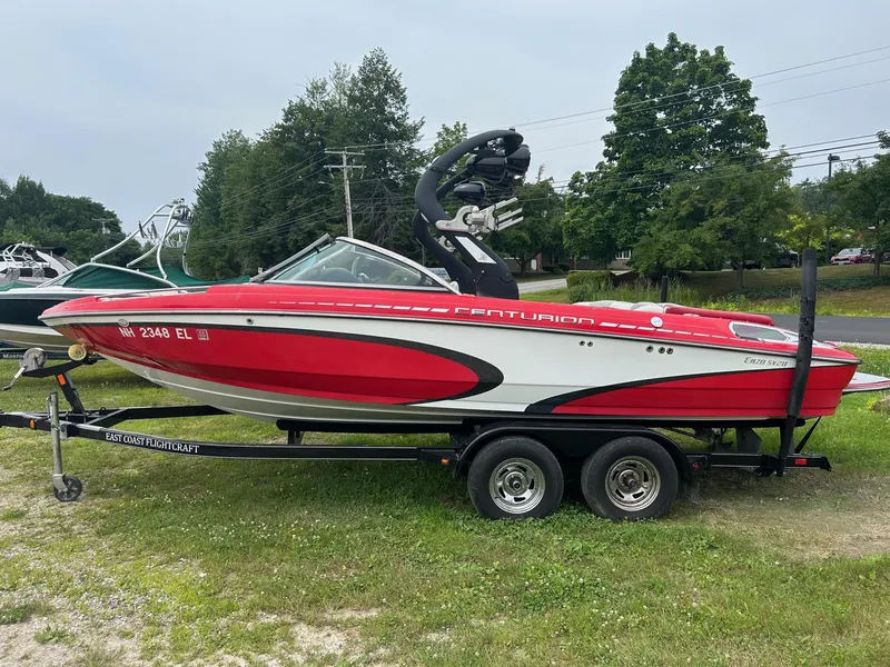 Slide: The Image of 2012 Centurion Enzo SV211 red and white boat on trailer, parked on grass. - 0