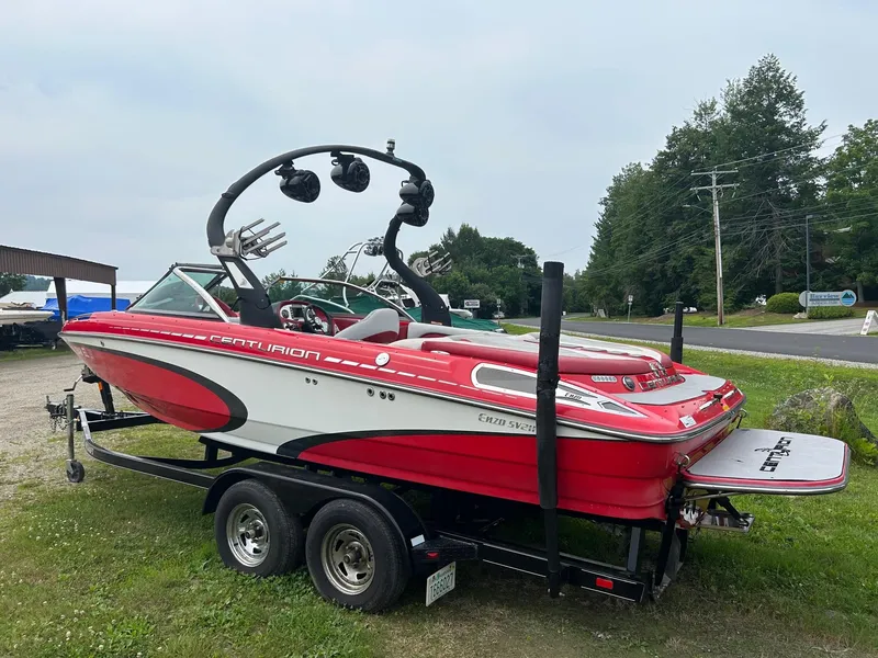 Slide: The Image of 2012 Centurion Enzo SV211 boat on trailer, red and white design, parked on grass. - 2