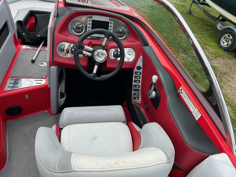 Slide: The Image of 2012 Centurion Enzo SV211 boat interior with red and gray seating and dashboard controls. - 4
