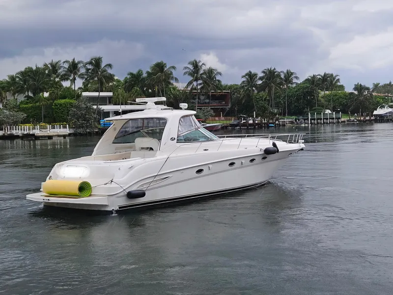 Slide: The Image of 2002 Sea Ray 460 Sundancer yacht cruising on a calm waterway with palm trees. - 2