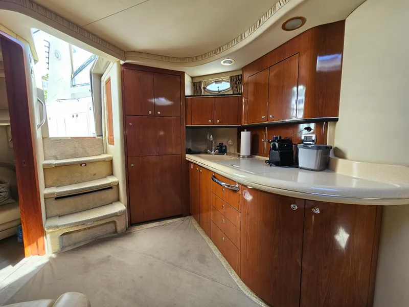 Slide: The Image of 2002 Sea Ray 460 Sundancer yacht interior with wooden cabinetry and kitchenette. - 23