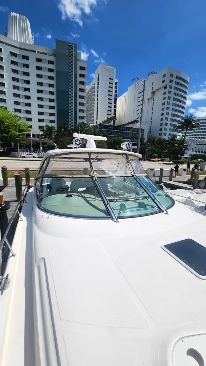 Slide: The Image of 2002 Sea Ray 460 Sundancer yacht docked near modern buildings under blue sky. - 4