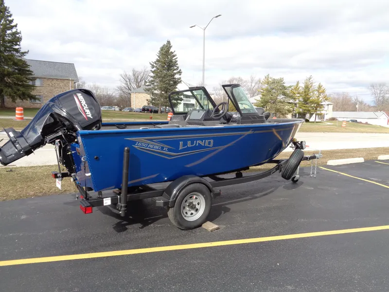 Slide: The Image of 2024 Lund 1650 Rebel XL Sport boat on trailer, parked outdoors. - 1
