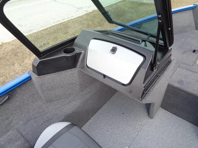 Slide: The Image of 2024 Lund 1650 Rebel XL Sport boat interior with open storage compartment and cup holder. - 19