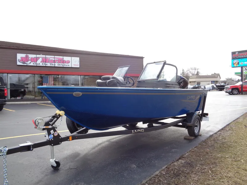 Slide: The Image of 2024 Lund 1650 Rebel XL Sport boat on trailer, parked outside a store. - 2
