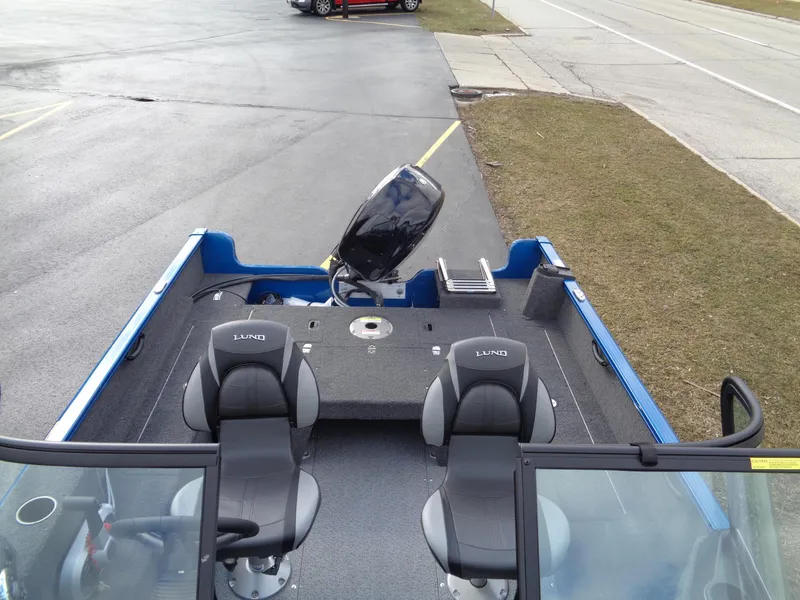 Slide: The Image of 2024 Lund 1650 Rebel XL Sport boat with dual seats and outboard motor, parked on pavement. - 8