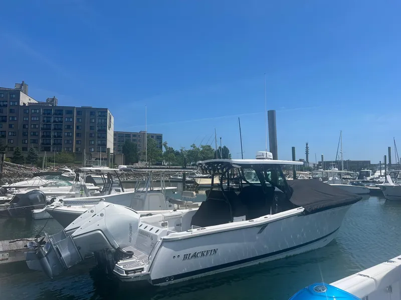 The Image of 2023 Blackfin 302 CC boat docked in marina, modern buildings in background. - 0