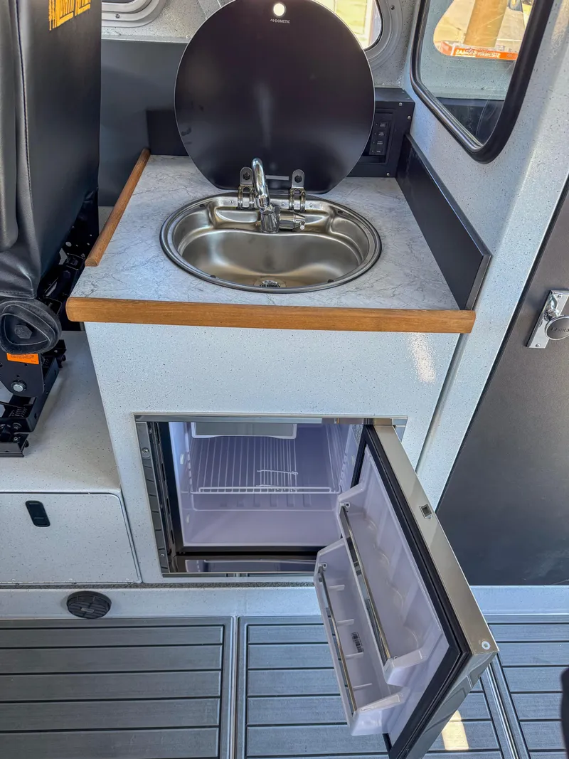 Slide: The Image of 2024 North River Seahawk OS 2700SXL boat interior with sink and mini-fridge. - 10