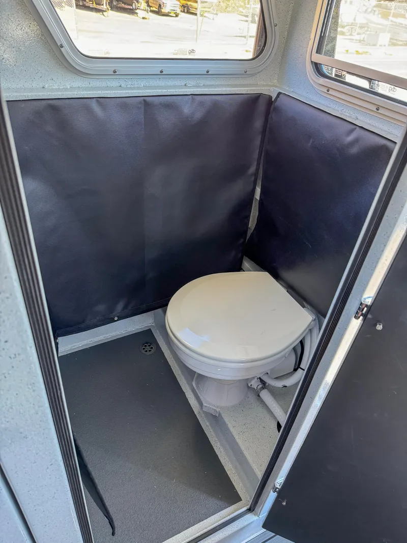 Slide: The Image of 2024 North River Seahawk OS 2700SXL boat interior with a compact marine toilet. - 12